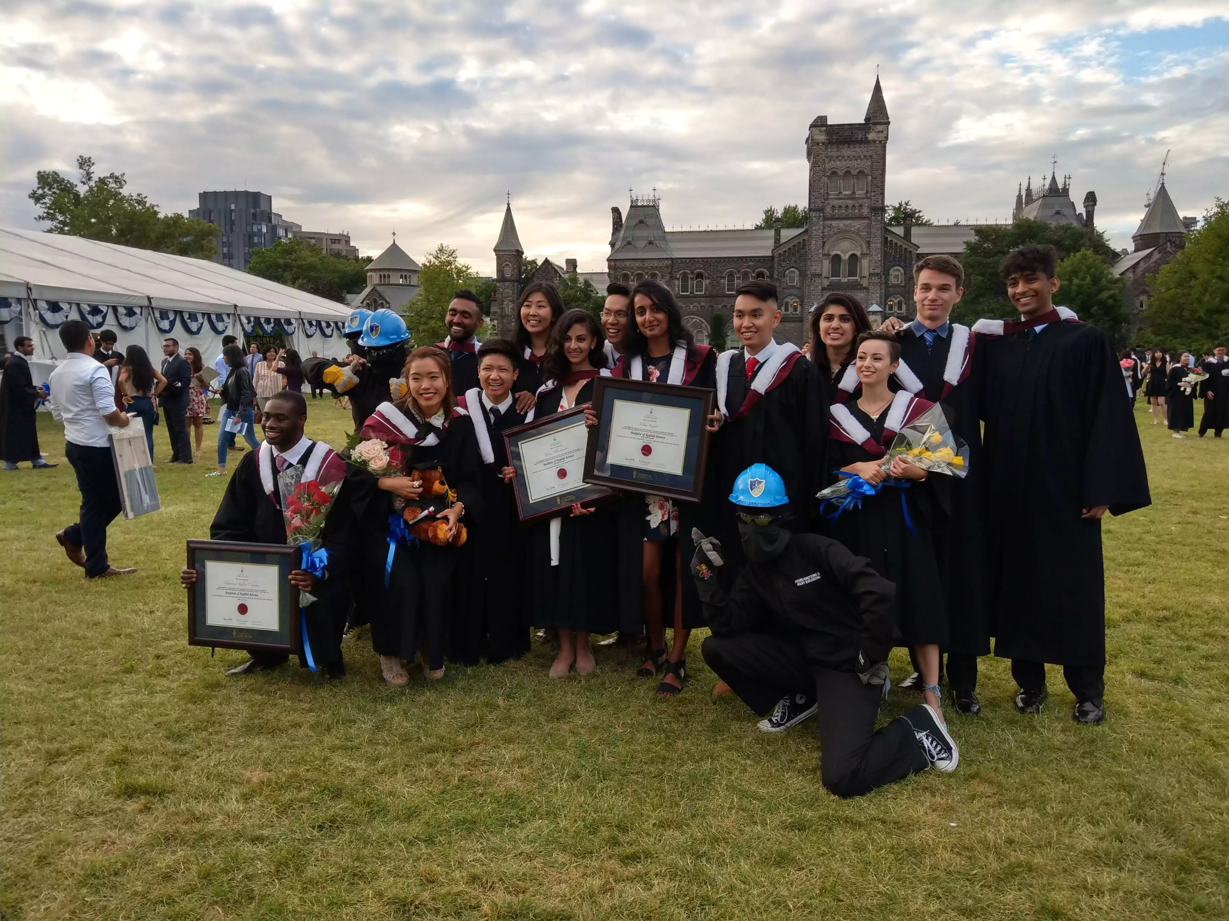 Students in graduation robes posing for a group photo on Kings College Circle, University of Toronto